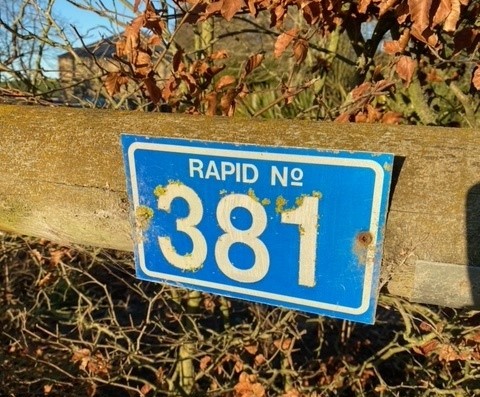 Image of a RAPID number plate on a fence post. 